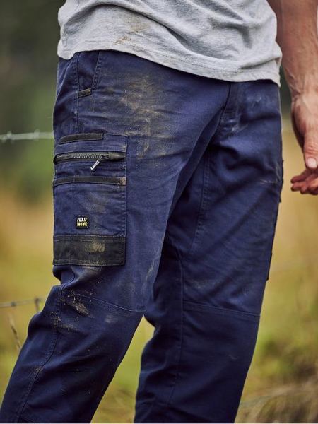 Person wearing blue work pants with multiple pockets in a natural setting