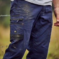 Person wearing blue work pants with multiple pockets in a natural setting